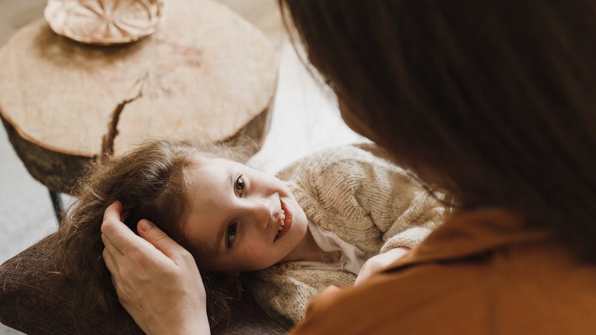Heartwarming image of a mother gently touching her daughter's hair indoors.